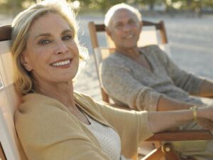 Beautiful senior couple sitting on beach in shade